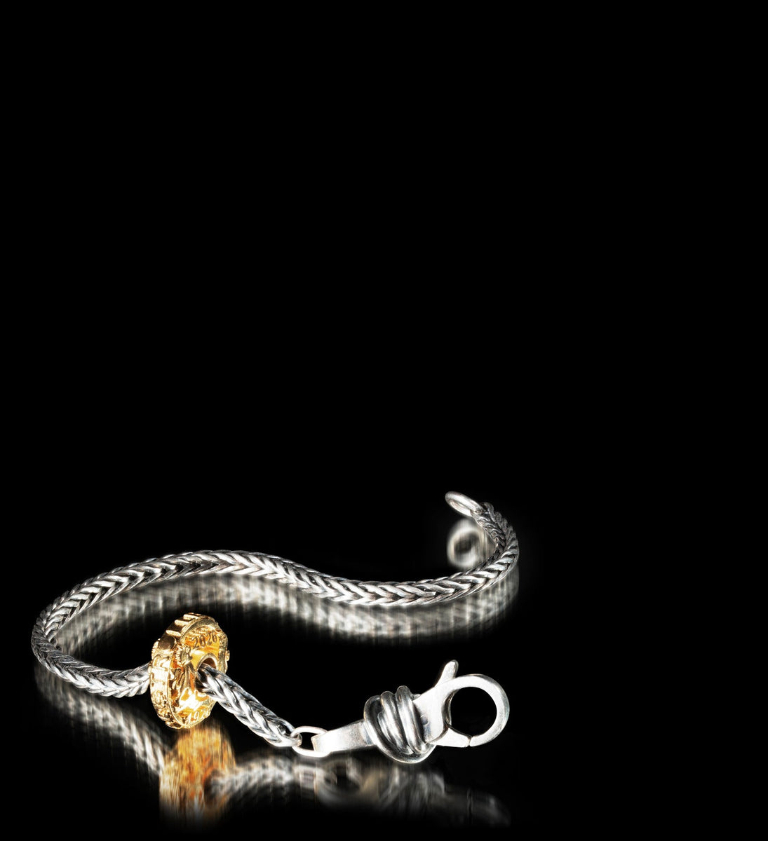 Silver bracelet with a gold-plated bead on a black background